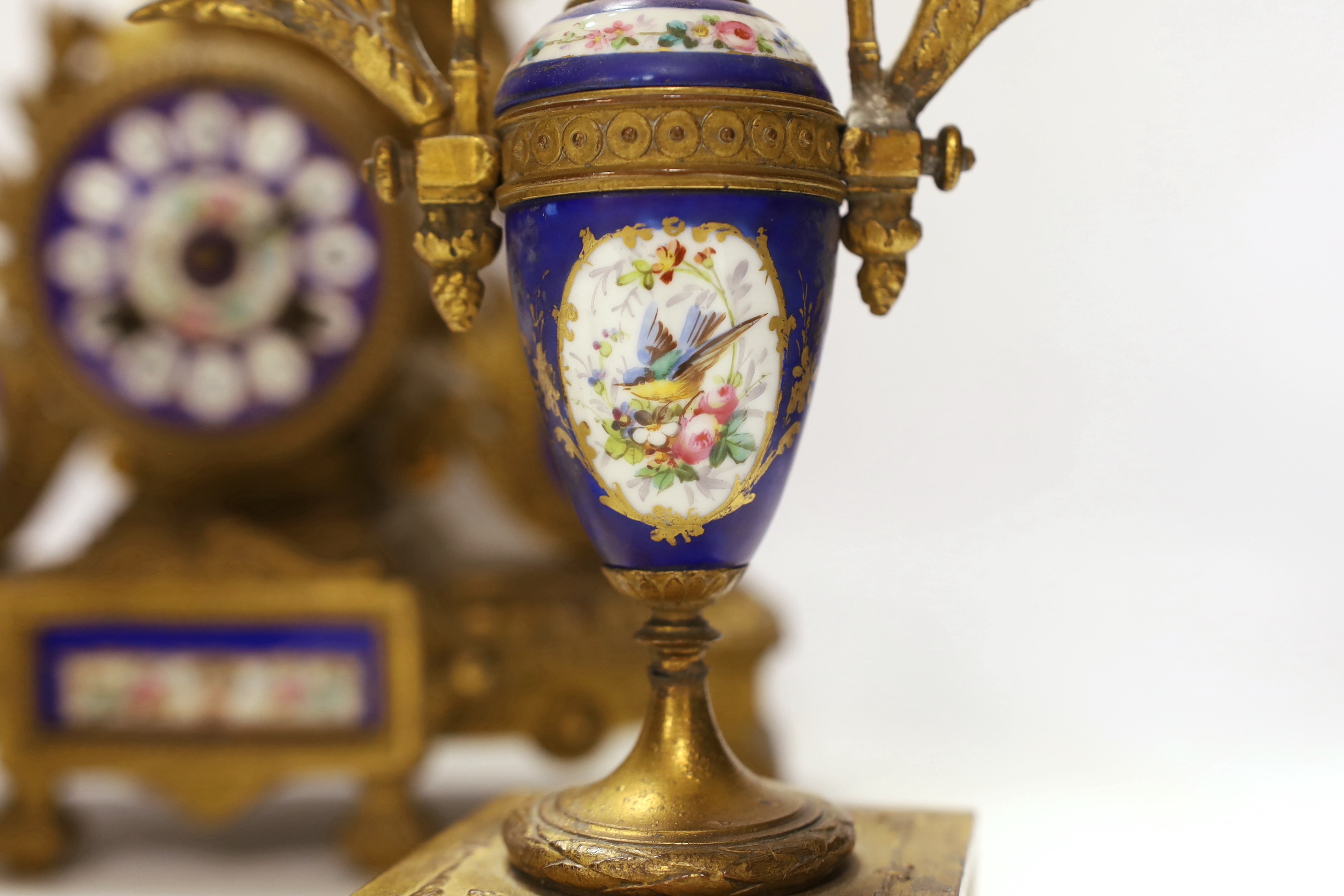 A 19th century ornate French gilt brass and porcelain clock, with two matching two branch candelabra garnitures, clock 31cm high